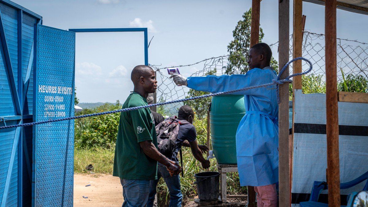 A worker takes the temperature of a visitor at Rwampara hospital in Rwampara, Ituri, Congo