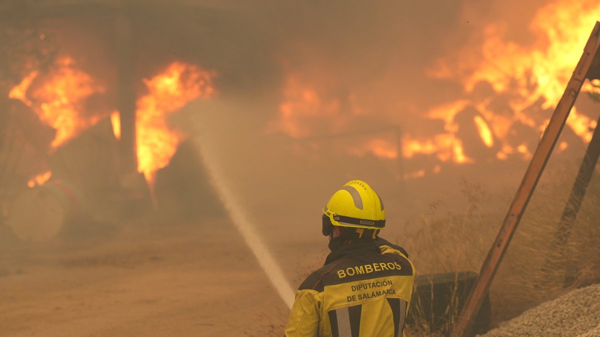 Un bombero rocía con agua neumáticos y barriles en llamas cerca de Ávila, España