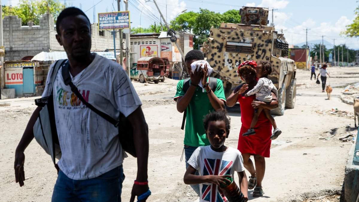 A family flees a neighborhood following gang riots that occurred the previous night in Port-au-Prince on April 20, 2026.