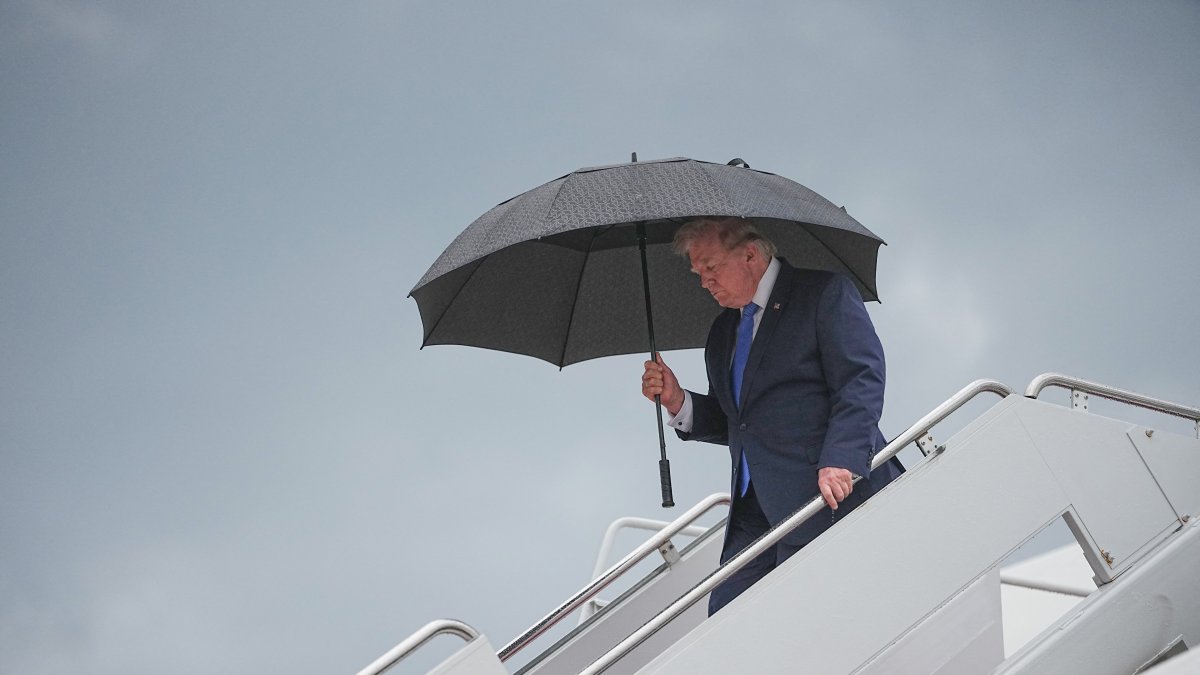 President Donald Trump walks under an umbrella as he disembarks from Air Force One at Joint Base Andrews in Maryland on August 2, 2026.