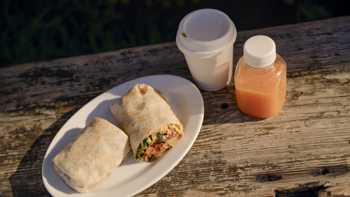Un burrito con un café y un zumo de naranja en una mesa en California