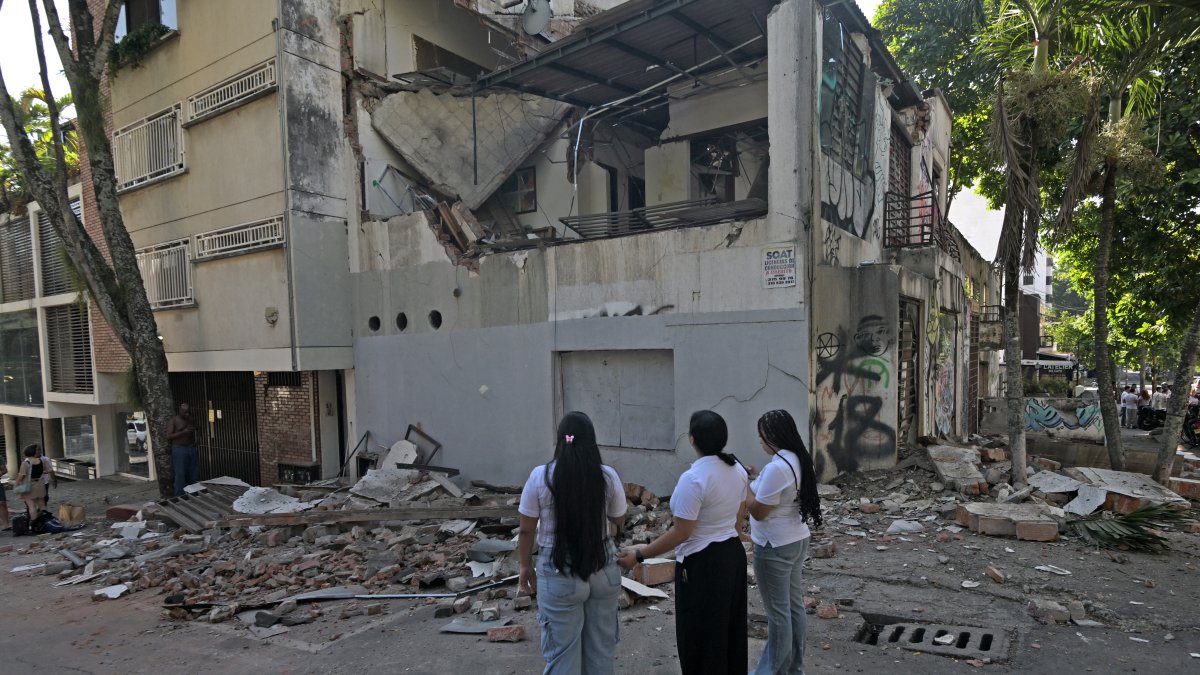 Women look at a collapsed building following the earthquake in Colombia