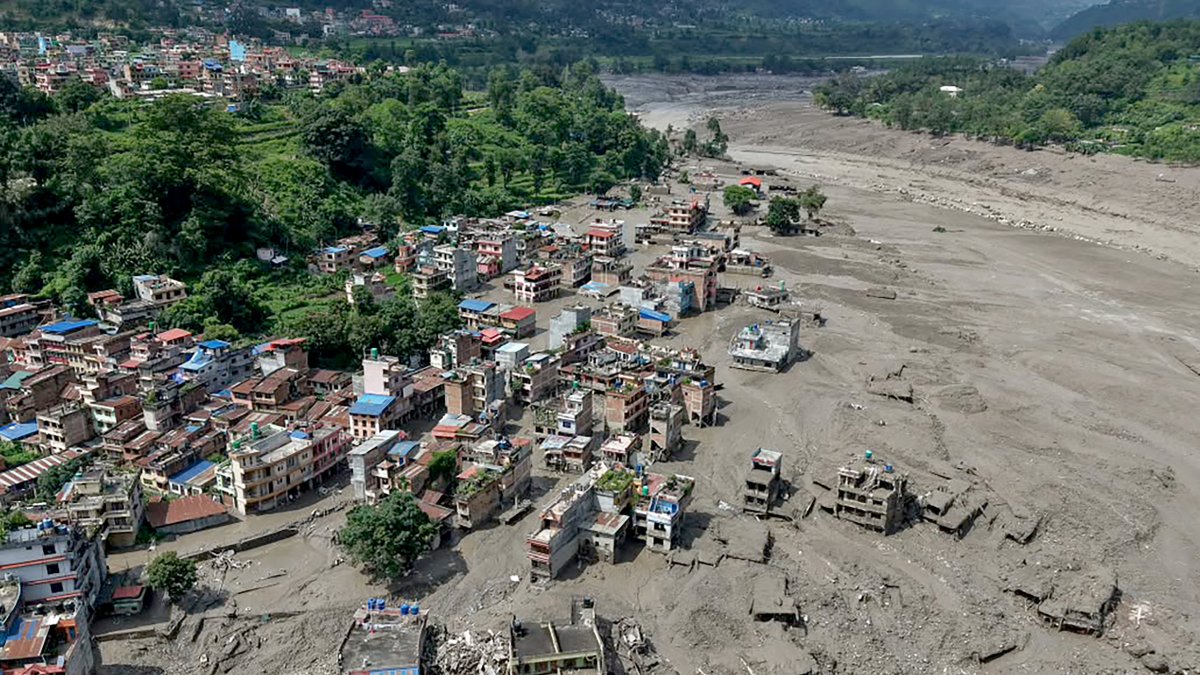 Several houses partially submerged in mud along a riverbank following flash floods in Trishuli Bazar, in the Nuwakot district.