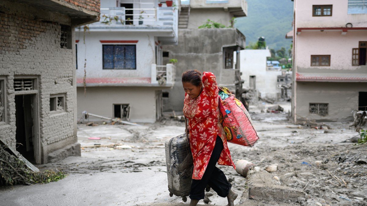 Una mujer rescata sus pertenencias de su vivienda tras las inundaciones repentinas en Nepal