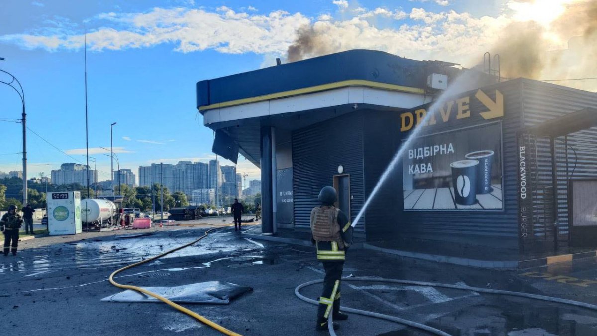 A police officer extinguishing a fire at a gas station following an attack by Russian drones