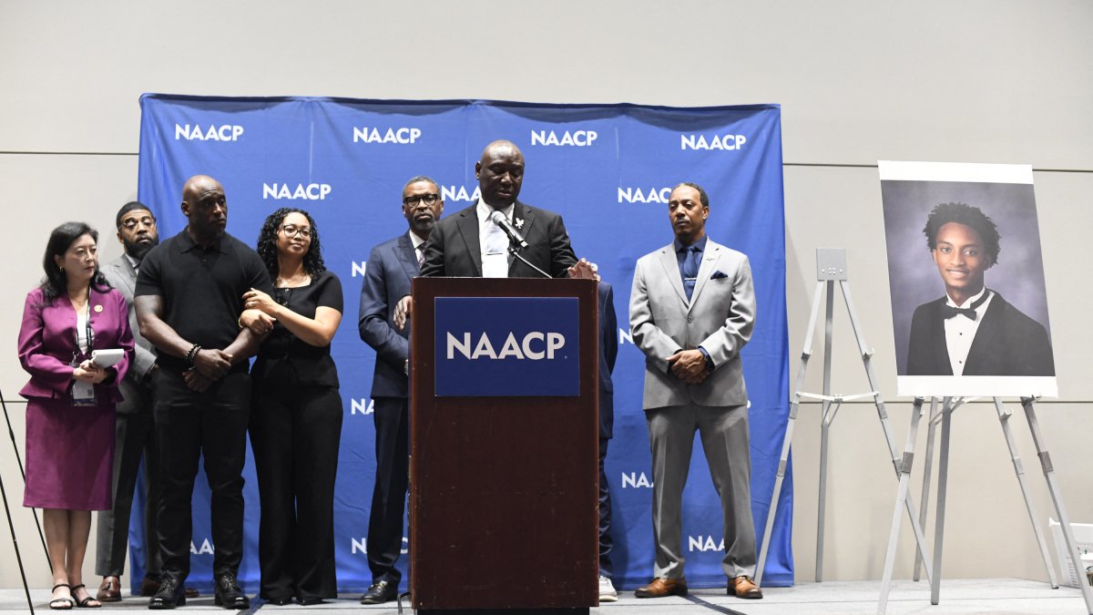 Ben Crump speaks at an event in front of Nolan Wells' parents