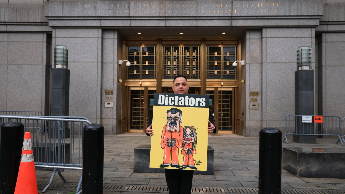 A protester holds a sign featuring an illustration of ousted Venezuelan President Nicolás Maduro and his wife, Cilia Flores.