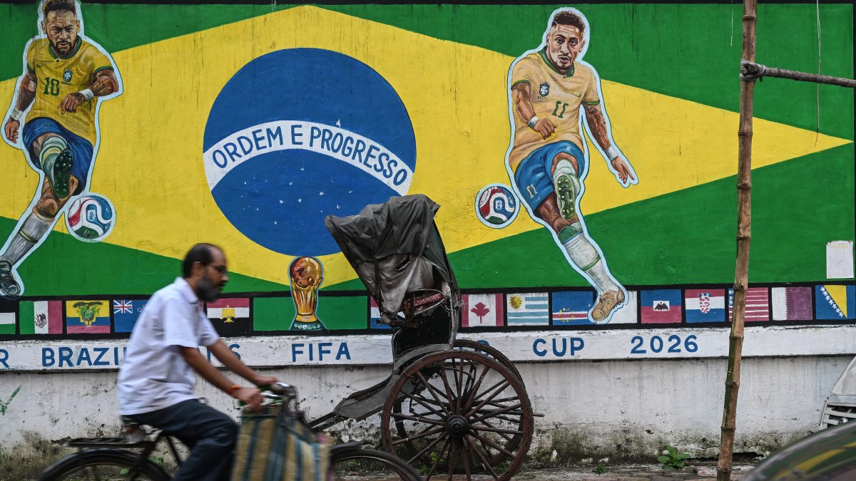 A cyclist rides past a piece of graffiti featuring images of Brazilian soccer player Neymar