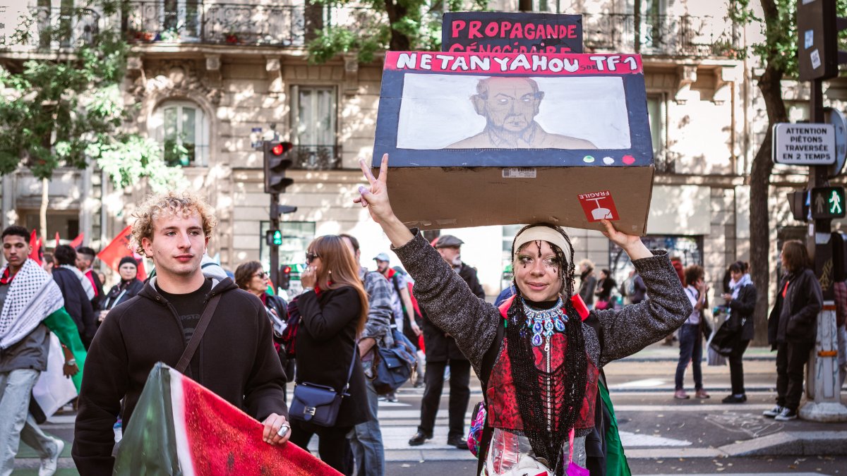 Protesters holding a banner and a sign during a demonstration in support of Palestine in Paris