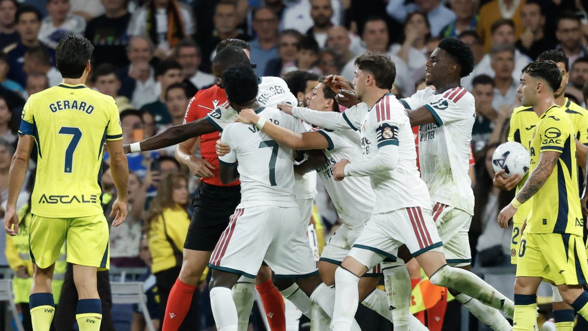 Real Madrid's Brazilian forward #07 Vinicius Junior (C) is restrained by teammates.
