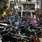 El 20 de septiembre de 2022, en la planta de camiones de Dearborn, Michigan, los trabajadores de Ford Motor Co. colocan los motores en el bastidor de los camiones F-150 de combustible en producción.