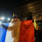 Un agricultor sostiene una bandera francesa frente al Arco del Triunfo.