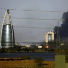 La imagen muestra la ciudad de Khartoum, capital de Sudán. Cerca de un edificio moderno, una columna de humo se eleva.