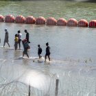 Crisis fronteriza: Migrantes caminan junto a una cadena de boyas colocadas en el agua a lo largo de la frontera del Río Grande con México en Eagle Pass, Texas,