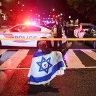 Un hombre con la bandera de Israel se acerca a la escena del crimen