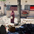 Una mujer lleva un recipiente de plástico en la escuela Mustafa Hafez, en la Franja de Gaza