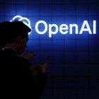 Visitor look at their phone next to an Open AI's logo