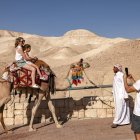 Tourists pose for a picture while riding camels near the sign marking mean sea level (Files)