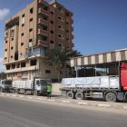 Trucks carrying aid provided by the World Food Programme (WFP) drive on a road in Deir el-Balah