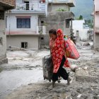 A woman salvages her belongings from her house heavily covered in mud following flash floods at Devighat in Nepals Nuwakot district on August 28, 2026. More than 1,400 people are missing and at least 552 have been killed after a devastating, tsunami-like wall of water gouged a path through the border region between Nepal and Tibet, sweeping away entire villages. (Photo by MANAN VATSYAYANA / AFP)