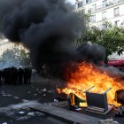 Agentes de policía custodian contenedores de basura y muebles incendiados en la calle durante una manifestación en París
