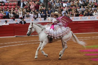 A girl rides a white horse in the bullring in Mexico City